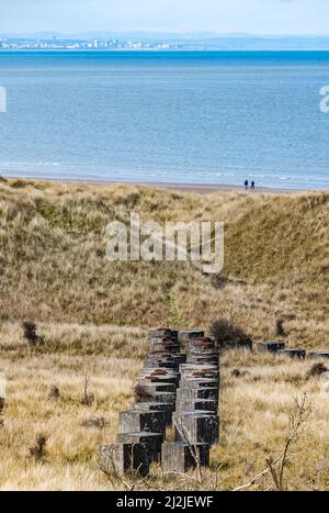 East Lothian, Scozia, Regno Unito, 2nd aprile 2022. UK Meteo: Sunshine on Aberlady Beach: La spiaggia lungo la costa Firth of Forth è quasi deserta con la bassa marea nonostante il sole primaverile. Nella foto: La vista sulla seconda guerra mondiale blocchi difensivi in cemento guardando verso il profilo di Edimburgo in lontananza Foto Stock