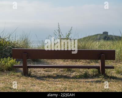 Un colpo posteriore di una panca di legno su erba verde fleid e cielo blu Foto Stock