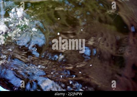 Grande puddle: La pioggia cade in un puddle e gocce d'acqua sulla superficie increspano Foto Stock