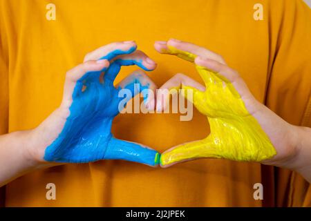 Amore Ucraina concetto. Mani in forma di cuore dipinto in Ucraina bandiera colore - giallo e blu. Fuoco selezionabile. Foto Stock