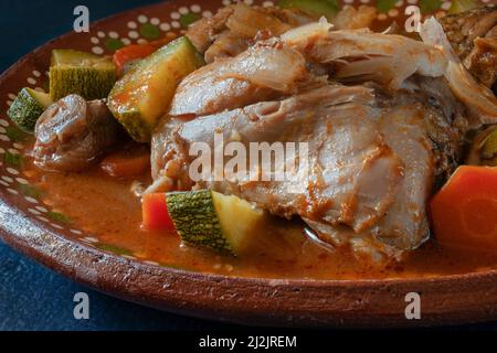 Pollo con verdure e salsa piccante di pomodoro in un piatto di argilla messicana. Mexicam concetto di cibo. Foto macro vista laterale Foto Stock
