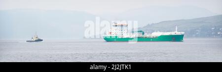 Nave che trasporta container galleggiante in mare seguito da rimorchiatore Foto Stock