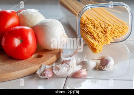 Macro fotografia, spaghetti crudi, crudi, crudi, con ingredienti su un tavolo, pronti per cucinare. Foto Stock