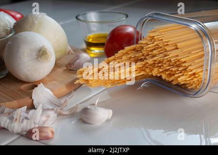 Macro fotografia, spaghetti crudi, crudi, crudi, con ingredienti su un tavolo, pronti per cucinare. Foto Stock