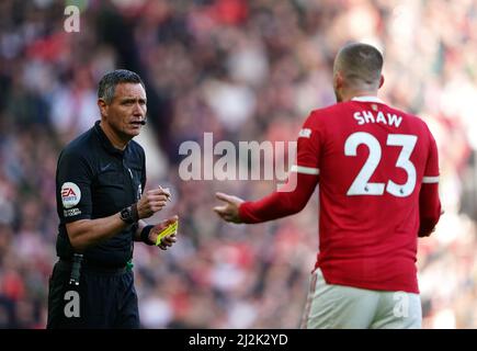 L'arbitro Andre Marriner mostra a Luke Shaw del Manchester United una carta gialla per il comportamento dissportivo durante la partita della Premier League a Old Trafford, Manchester. Data foto: Sabato 2 aprile 2022. Foto Stock