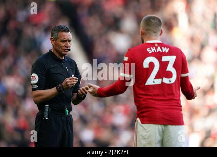 L'arbitro Andre Marriner mostra a Luke Shaw del Manchester United una carta gialla per il comportamento dissportivo durante la partita della Premier League a Old Trafford, Manchester. Data foto: Sabato 2 aprile 2022. Foto Stock