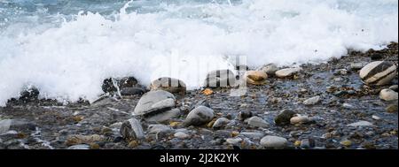 Variation de galets dans vagues et écume Foto Stock