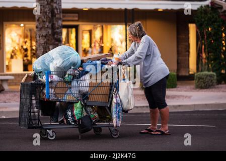 Vecchia donna senza tetto che spinge un carrello con i suoi effetti personali nel centro di Scottsdale, Arizona, Stati Uniti Foto Stock
