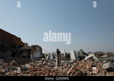 Una ragazza solitaria in un cappotto e jeans sulle rovine di una casa rovinata. Conseguenze del grano di guerra effetto Foto Stock