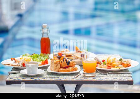 Tavolo con cibo delizioso vicino alla bella piscina blu viaggio nel resort Foto Stock