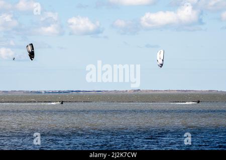 Norddeich, Germania. 02nd Apr 2022. I kitesurfers sono fuori sul Mare del Nord in tempo di sole, mentre l'isola di Juist può essere vista sullo sfondo. Il 04.04.2022 iniziano le vacanze pasquali nella bassa Sassonia, a Brema e nello Schleswig-Holstein. Credit: Hauke-Christian Dittrich/dpa/Alamy Live News Foto Stock