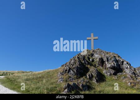 Stone Cross contro Blue Sky a Llanddwyn Island, Anglesey, Galles del Nord, Regno Unito. Foto Stock