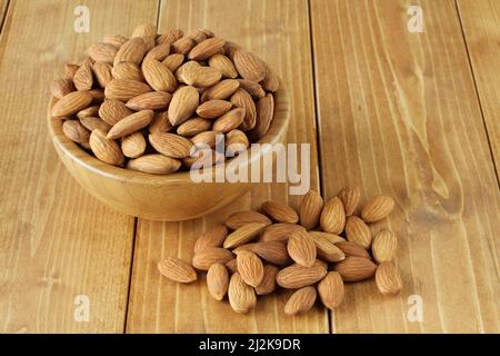 Grandi mandorle sgusciate in ciotola di bambù su tavola di legno. Primo piano. Foto Stock