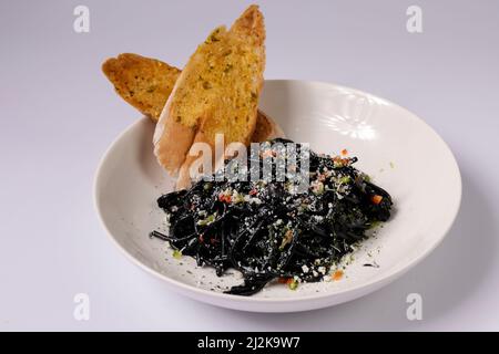 Spaghetti neri pasta negra iwith aglio pane in un piatto vista dall'alto su sfondo grigio singapore food Foto Stock