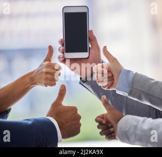 Weve ha ottenuto la nostra idea di milione dollari proprio qui. Il colpo corto di un gruppo irriconoscibile di uomini d'affari in piedi con i loro pollici in su mentre un collega Foto Stock