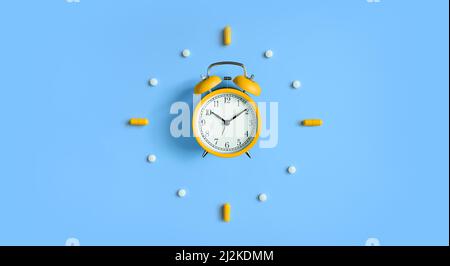 Sveglia con pillole, capsule mediche su sfondo blu Foto Stock