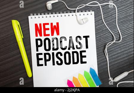 Vista superiore del podcast di apparecchiature di registrazione su tavola in legno rustico con parole un nuovo episodio di podcast scritto sul blocco note a spirale Foto Stock