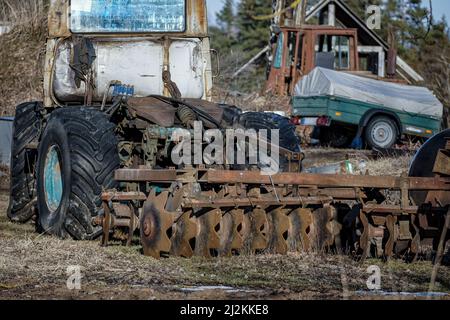 Abbandonate vecchie macchine agricole arrugginite e attrezzature nella fattoria Foto Stock