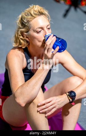 Vera giovane caucasica matura donna in uno sport indossare acqua potabile in palestra. Concetto di fitness. Foto Stock