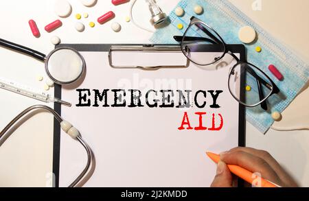 primo piano di un manuale di pronto soccorso di emergenza con occhiali neri appoggiati sulla parte superiore. Cosa fare in uno scenario di incidente d'emergenza. Foto Stock