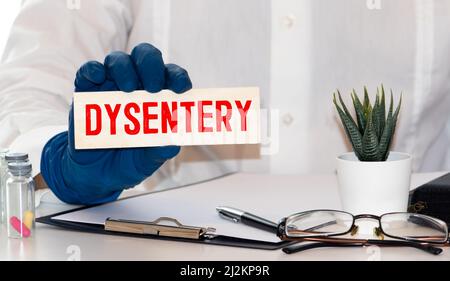 Il medico tiene una scheda con il nome della dissenteria di diagnosi. Messa a fuoco selettiva. Concetto medico. Foto Stock