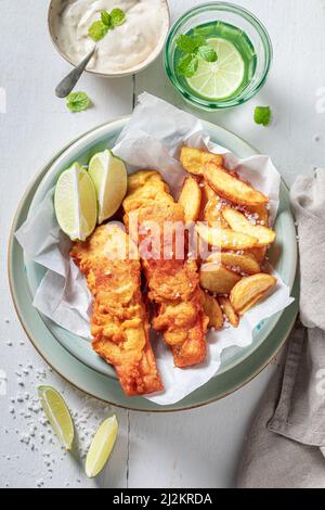 Pesce alla griglia e patatine con salse e lime. Merluzzo fritto con patatine fritte servite con lime. Foto Stock