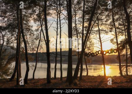 Magnifico tramonto, grande laghetto e riflessi luminosi in acqua. Cielo arancione e silhouette nere di alberi. La bellezza della natura in Turchia. Foto Stock