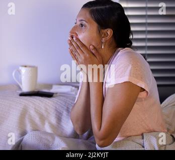 Non credo che sia appena accaduto. Scatto di una giovane donna che guarda scioccata mentre guarda la tv a casa. Foto Stock