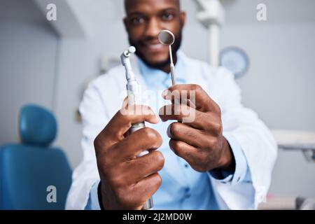 Un sorriso meravigliosamente luminoso che arriva fino in alto. Ritratto di un giovane uomo che tiene i denti strumenti di pulizia nel suo studio dentistico. Foto Stock