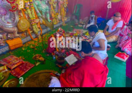 Immagine sfocata della Dea Durga è adorata da sacerdoti indù mascherati durante sondhipujo aarti. Durga puja durante la pandemia di Covid 19. Foto Stock