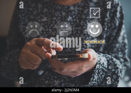 Feedback del sondaggio del cliente e concetto di servizio di soddisfazione. Le mani della donna sta scegliendo il tasso di valutazione di soddisfazione per il servizio di cliente. Qu. Prodotto Foto Stock