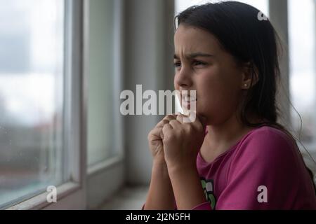 Bambina che prega sul tavolo bianco la mattina. La mano della bambina che prega, le mani piegate nel concetto di preghiera per la fede, la spiritualità e la religione. Foto Stock