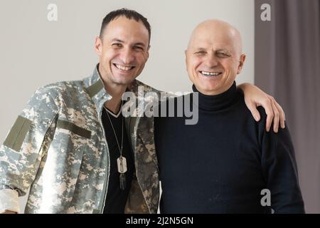 Il padre militare abbraccia suo figlio quando si riunì dopo una missione Foto Stock