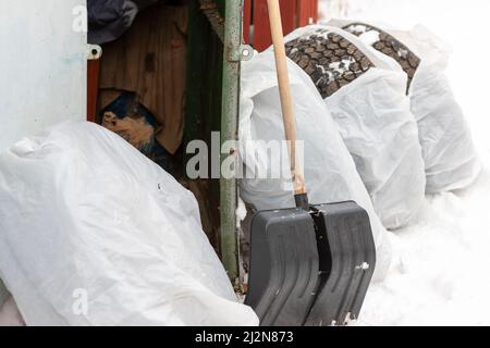 rimozione della neve e set di pneumatici avvolti in sacchetti di plastica e porta aperta di un garage Foto Stock