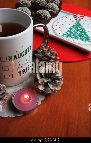 Palle dolci di cioccolato di Natale, alberi e cono di pino vicino alla tazza di tè Foto Stock