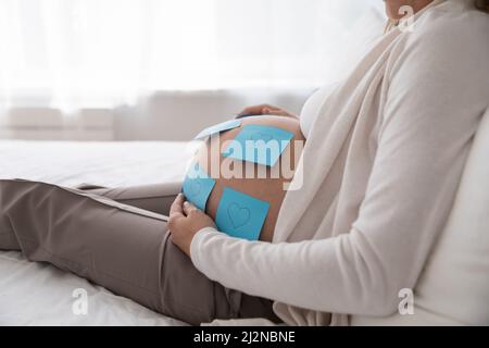 Grande bump del bambino in primo piano con i simboli di amore del cuore Foto Stock