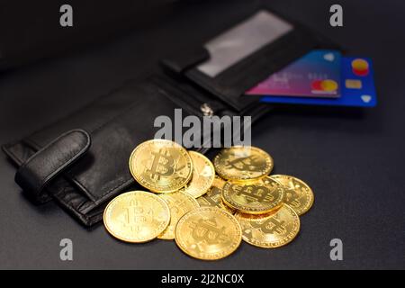 Monete Bitcoin e carte di credito in un portafoglio sullo sfondo della lavagna Foto Stock