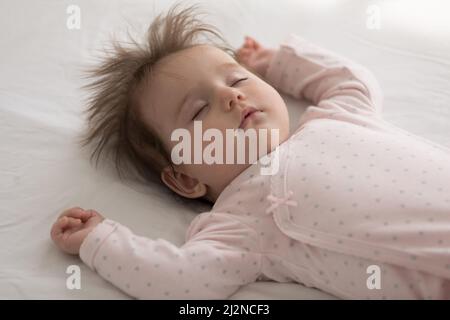 Baby girl silenziosa e sonnolenta in un panno rosa sdraiato sulla schiena Foto Stock