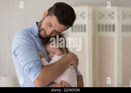 Calma nuovo papà tranquillo abbraccio, stringendo sonnolento bambino Foto Stock