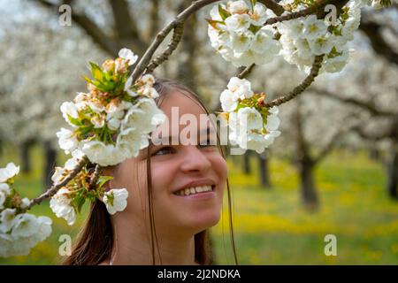 Ritratto di una giovane donna che indossa un abito bianco in un frutteto di ciliegio con alberi in fiore. Primavera estate immagine .provenza , Francia . Foto Stock