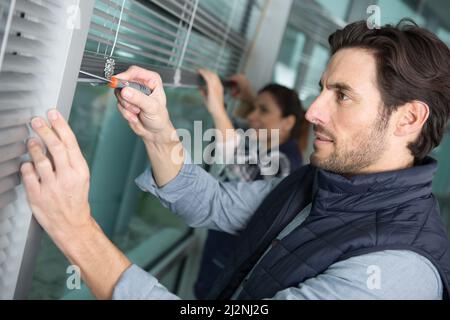 uomo e donna che installano tende per finestre Foto Stock