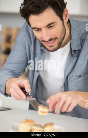 uomo che prepara tapas per i visitatori a casa Foto Stock