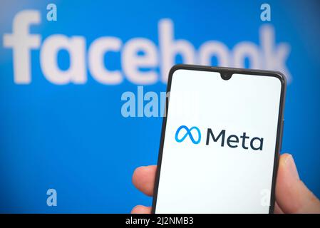 Wroclaw, Polonia - Apr 01, 2022: Facebook cambia il nome della sua azienda in Meta. Meta su uno smartphone e logo Facebook sullo sfondo Foto Stock