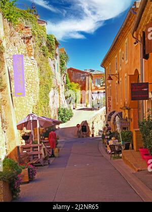 Roussillon en Provence, Francia - Ottobre 2. 2019: Vista su strada vicolo con muro di pietra naturale della fortezza e mediterraneo ocra case giallo ancora Foto Stock