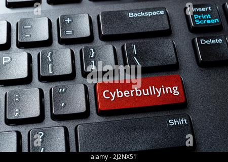 Сyberbullying parola sul pulsante della tastiera di un computer. Il notebook inserisce la chiave con messaggi di cyberbullismo. Concetto di scrittura intimidita, abusiva e minacciosa. Foto Stock