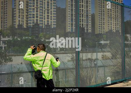 Hong Kong, Cina. 03rd Apr 2022. Un uomo parla mentre guarda i suoi parenti attraverso il binocolo a Shenzhen attraverso la recinzione di confine a Heung Yuen Wai a Hong Kong. Situato al confine tra Hong Kong e Shenzhen, Hung Yuen Wai è uno dei luoghi in cui le famiglie separate dal confine a causa delle restrizioni di viaggio covid-19 possono vedersi a vicenda. Credit: SOPA Images Limited/Alamy Live News Foto Stock