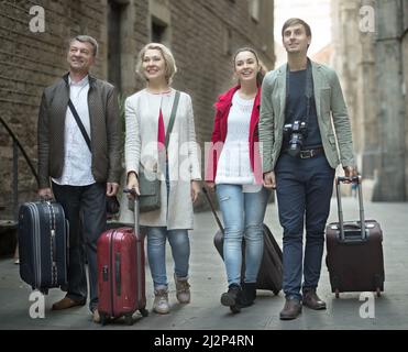 I turisti con valigie e macchina fotografica camminano lungo le strade storiche della città europea Foto Stock