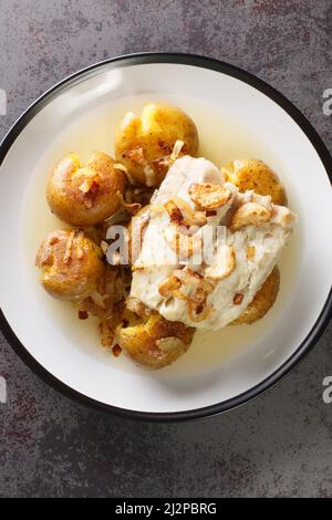 Tradizionale portoghese Bacalhau un forno Lagareiro cotto Pesce Codfish con patate primo piano nel piatto sul tavolo. Vista dall'alto verticale Foto Stock