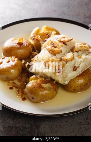 Tradizionale portoghese Bacalhau un forno Lagareiro cotto Pesce Codfish con patate primo piano nel piatto sul tavolo. Verticale Foto Stock