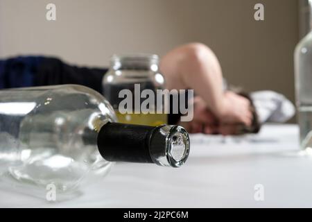 Un uomo ubriaco si trova a letto, tenendogli le mani in testa. Hangover, delirio alcolico. Foto Stock